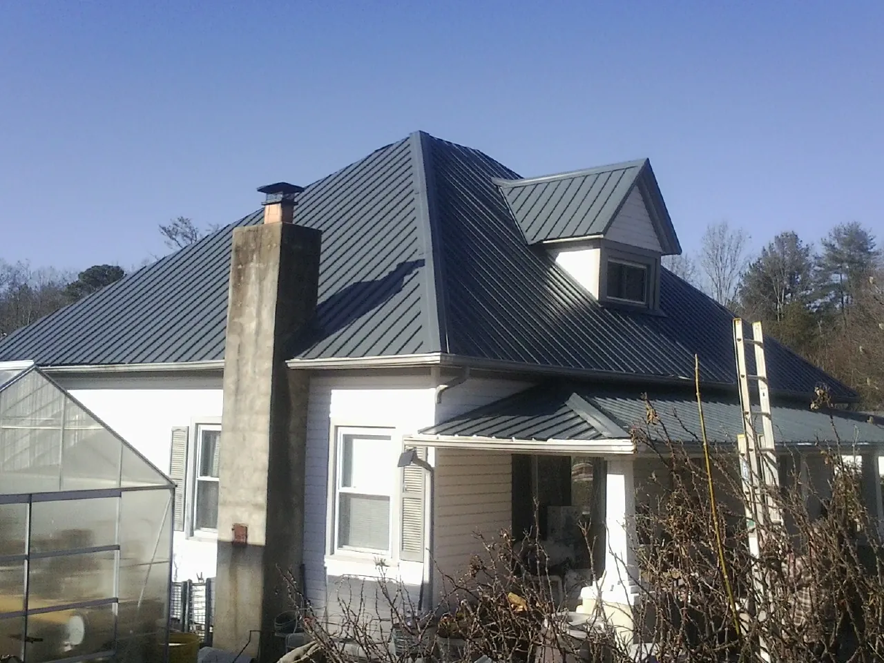 Dark blue standing seam metal roof on a white farmhouse with dormer — Slate & Tile Roof Repair by Roofing Brothers in Greenbrier