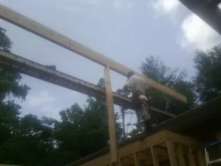 Carpenter setting a ridge beam over a new addition frame — Ice Dam Removal by Roofing Brothers in Greenbrier