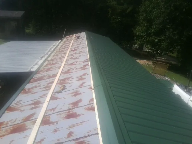 Old rusted panels beside newly installed green metal roofing — Wind Damage Roof Repair by Roofing Brothers in Greenbrier