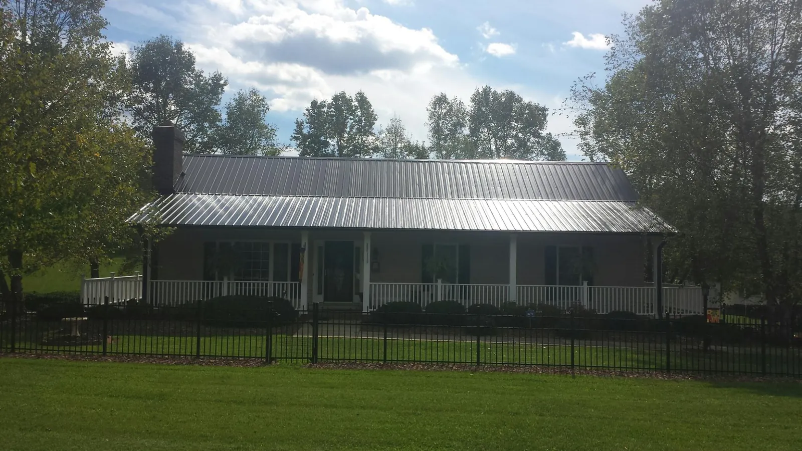 Gray metal roof on a brick ranch with a full width front porch — Gutter Guard Installation work by our crew in Greenbrier