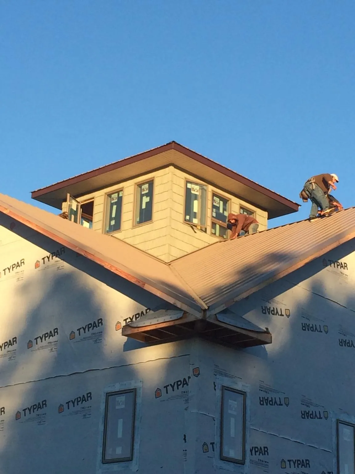 Roofers working around a rooftop cupola on a new metal roof at sunset — Roof Waterproofing in Greenbrier by Roofing Brothers